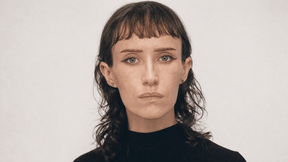 Seedance 2_0 - she sits still with subtle movement_ slightly adjusting in her seat.gif