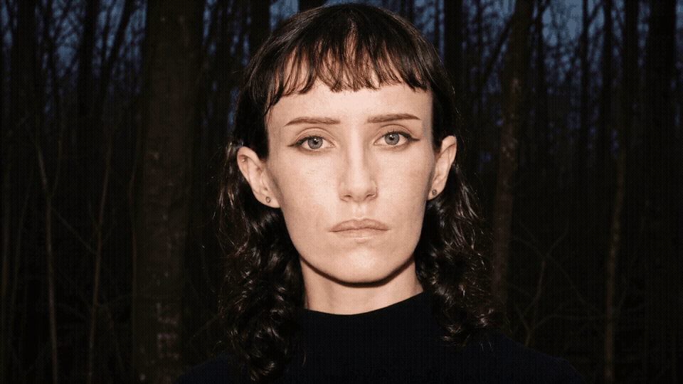 Aleph 2_0 - Seedance 2_0 - she sits still with subtle movement_ slightly adjusting in her seat (1).gif